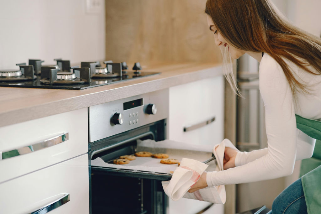 A woman putting a baking tray in the oven
