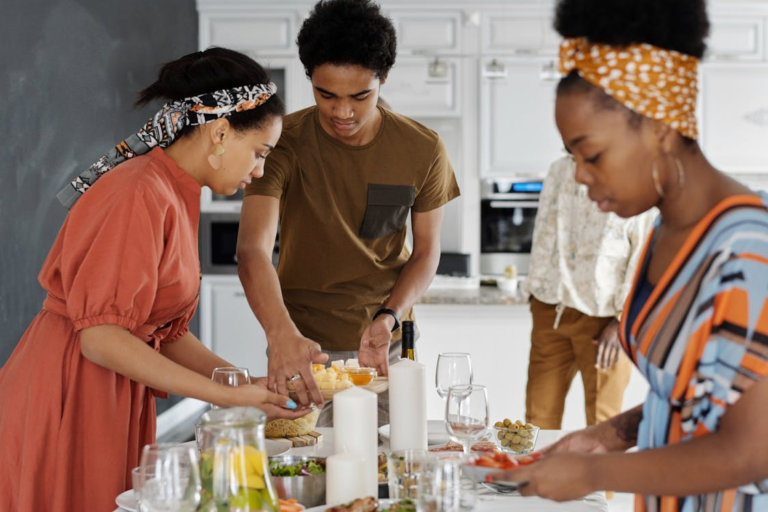 A group of people preparing vegetables and holiday dishes together in a bright kitchen