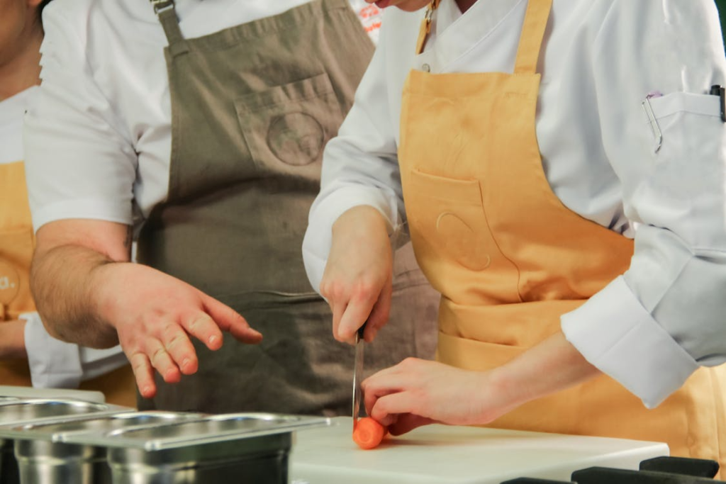 A person teaching another how to chop vegetables